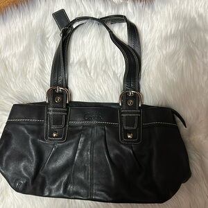 Black leather coach bag with silver buckles.